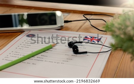 English listening test with earphone and tablet on wooden desk