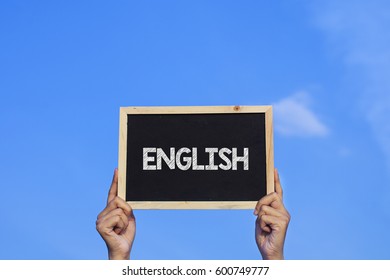 ENGLISH / Man holding small blackboard on blue sky background - Shutterstock ID 600749777