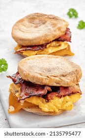 English Muffin, Scrumbled Egg, Ham, And Cheese Breakfast Sandwich On A Cutting Board