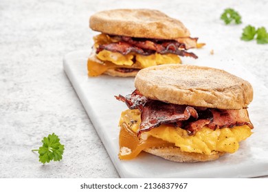 English muffin, scrumbled egg, ham, and cheese breakfast sandwich on a cutting board - Powered by Shutterstock