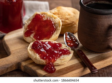 English muffin spread with strawberry preserves on a wooden cutting board - Powered by Shutterstock