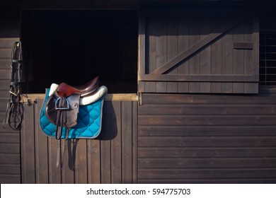 English saddle and bridle hanging on a wooden stable door UK - Shutterstock ID 594775703