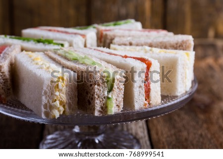 English tea sandwiches on cake over rustic wooden background 