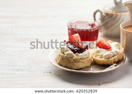 English tea with scones and clotted cream, jam, strawberries on the white table, copy space for text, selective focus