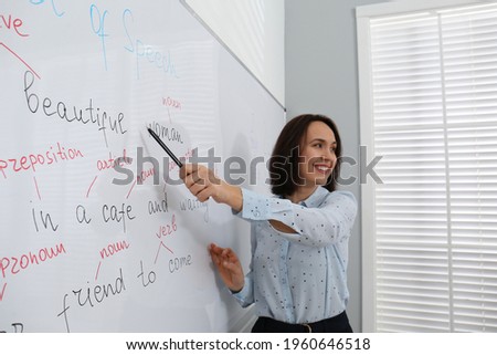 English teacher giving lesson near whiteboard in classroom