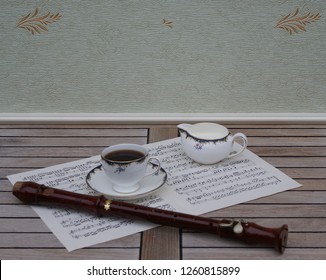 English Teacup With Saucer And Cream Jug, Fine Bone China Porcelain, And A Block Flute On A Sheet Of Music