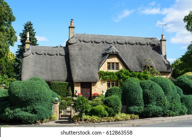An English thatched cottage built out of Cotswold stone with a beautiful hedge in the garden in Chipping Campden, the Cotswolds, England, UK.