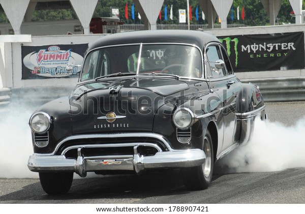 Englishtown, NJ / USA - July 3, 2016: A vintage\
souped-up Oldsmobile performs a burnout during a nostalgia drag\
racing event in Englishtown, New\
Jersey.