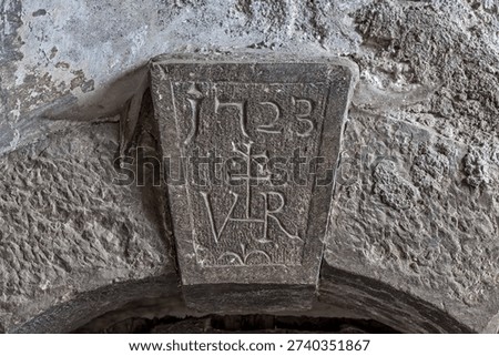 Engraved stone keystone dated 1723 with symbolic carvings, ideal for heritage architecture and historical documentation.