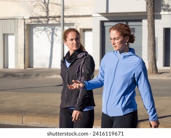 Engrossed in discussion, twin sisters walk together on a city street, enjoying the sunny weather and each other's company - Powered by Shutterstock