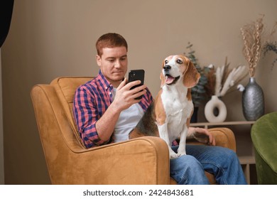 Engrossed in his phone, the man finds company with his loyal dog; their bond unshaken by the distractions of technology. - Powered by Shutterstock