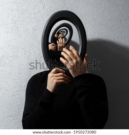 Enigmatic surrealistic optical illusion, young man holding round frame on textured grey background. Contemporary artwork collage concept.