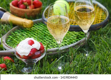 Enjoing in Wimbledon tennis championship with champagne and strawberries with cream. Wimbledon symbols on green grass.
