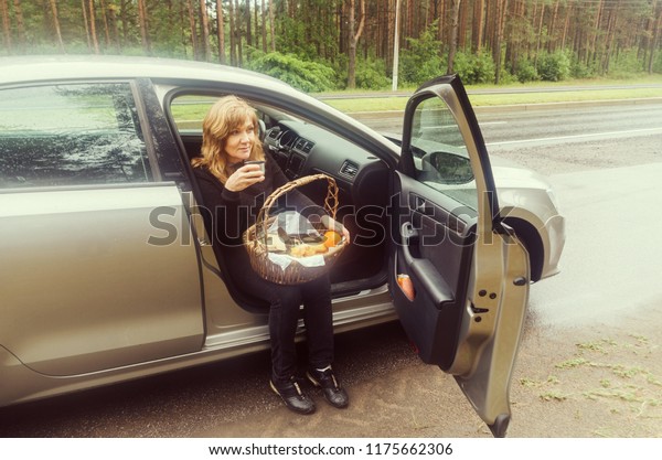 Enjoy autumn\
nature. Beautiful elderly woman with a picnic basket in a car.\
Quick meal on a road. Enjoy\
retirement.