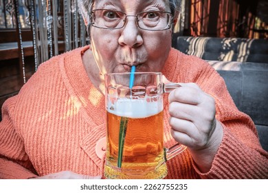 Enjoy delicious fresh beer. Elderly woman drinking beer in a cafe. 