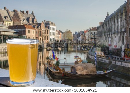 Enjoy glass of light beer with view of canal and historic buildings in Ghent, Belgium