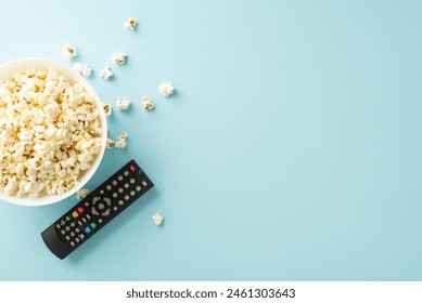 Enjoy home cinema with premieres using TV app. Top-view shot of popcorn, and remote for online viewing on pastel blue backdrop - Powered by Shutterstock