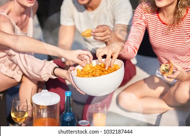 Enjoy it. Close up of bowl with snacks in hands of a young woman holding it while sharing with her friends