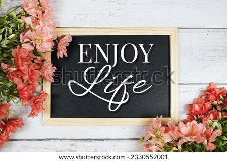 Enjoy Life text on blackboard with flower bouquet decoration
