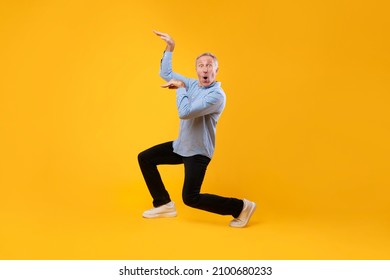 Enjoy The Music Concept. Happy excited funny mature man dancing to favorite song isolated over yellow orange studio background wall, copy space. Senior male doing disco moves enjoying sound, banner