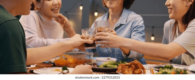 Enjoy soda drink glass toast at dine table happy hour cheers to retire middle aged mom. Group of asia people young adult woman friend and mum fun joy relax warm time night thai meal party at cozy home - Powered by Shutterstock