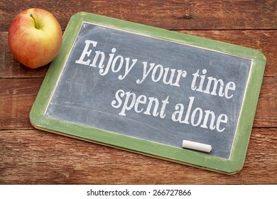 Enjoy Your Time Spent Alone - Positive Words On A Slate Blackboard Against Red Barn Wood