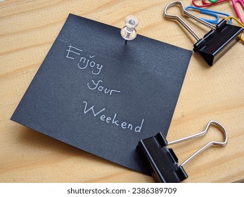 enjoy your weekend, hand write on black sticky note and wood background