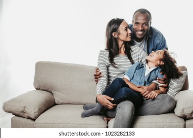 Enjoyed parents and child sitting together with comfort. Mom and kid are looking at father standing abaft them. Copy space in left side. Isolated on background స్టాక్ ఫోటో