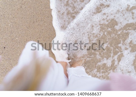 Enjoying the beach and the sea water. View of the feet and the waves of the white skirt