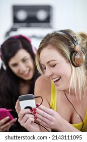 Enjoying the beat. Two young female friends listening to music on a mp3 player together.