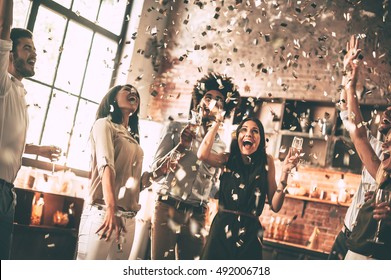 Enjoying bright moments. Cheerful young people throwing confetti and smiling while enjoying home party on the kitchen  - Shutterstock ID 492006718