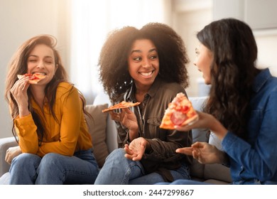 Enjoying a casual meal, three multiracial women eat pizza and converse in a warm and friendly environment at home - Powered by Shutterstock