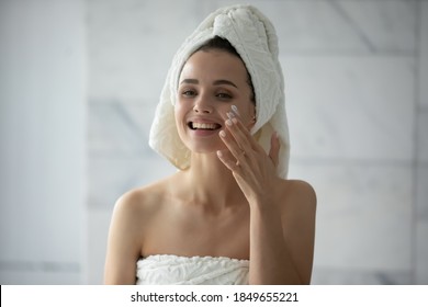 Enjoying Domestic Care. Happy Smiling Millennial Woman Having Pleasure Treating Her Skin At Home, Applying Facial Mask Cream Lotion After Bath Procedures Using Favorite Cosmetics Satisfied With Result