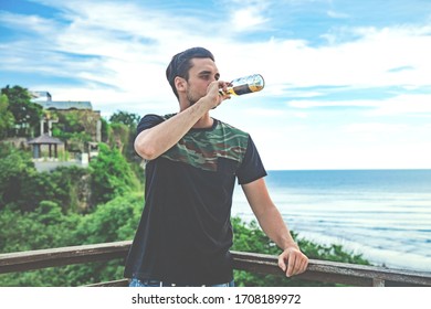 Enjoying drinking beer and looking at distant seascape on a vacation.