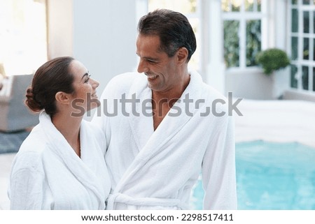 Enjoying each others company at the pool. a couple in robes beside a pool.