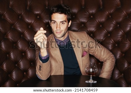 Enjoying the finer things. Portrait of a handsome young man drinking in a club.