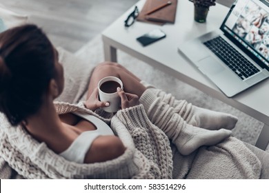 Enjoying Fresh Coffee. Top View Of Beautiful Young Woman Holding Cup While Relaxing On Couch At Home