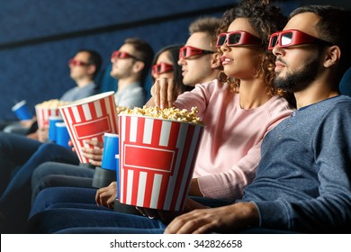 Enjoying A Great Movie. Shot Of A Group Of Friends Watching A Movie Eating Popcorn Drinking Beverages