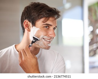 Enjoying his morning routine. Cropped shot of a young man shaving his facial hair with a disposable blade. - Powered by Shutterstock