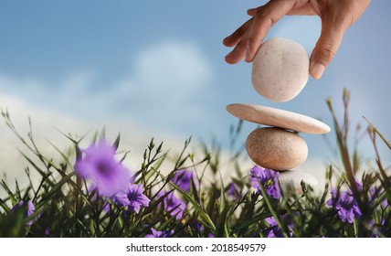 Enjoying Life Concept. Harmony and Positive Mind. Hand Setting Natural Pebble Stone with Smiling Face Cartoon to Balance Flower Garden. Balancing Body, Mind, Soul and Spirit. Mental Health Practice