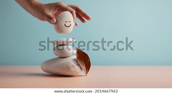 Enjoying\
Life Concept. Harmony and Positive Mind. Hand Setting Natural\
Pebble Stone with Smiling Face Cartoon to Balance. Balancing Body,\
Mind, Soul and Spirit. Mental Health\
Practice