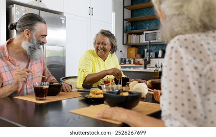 Enjoying meal together, group of senior friends laughing and dining at home. Friendship, seniors, laughter, socializing, togetherness, unaltered - Powered by Shutterstock