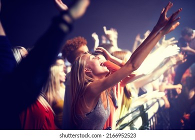 Enjoying the music. A group of people standing with their arms raised at a concert. - Powered by Shutterstock