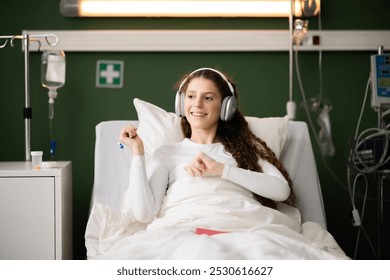 Enjoying music, the patient wears headphones in her comfy bed in hospital ward. - Powered by Shutterstock