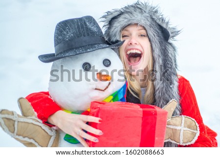 Enjoying nature wintertime. Well dressed enjoying the winter. Winter clothes for woman. Happy girl playing with a snowman on a snowy winter walk