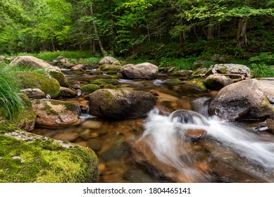 Enjoying a peaceful moment by the river where the water flows around some rocks covered with a green moss. Photo taken in Mont-Mégatic National Park, Quebec, Canada. - Powered by Shutterstock