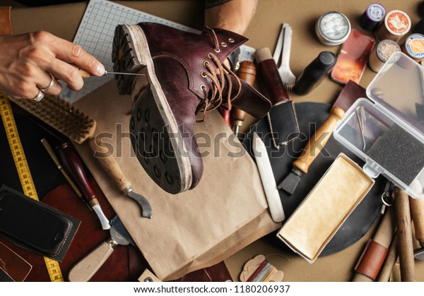 Enjoying process of creation custom made shoes.\
Workplace of shoe designer. Hands of shoemaker dealing with cobbler\
tool, close up