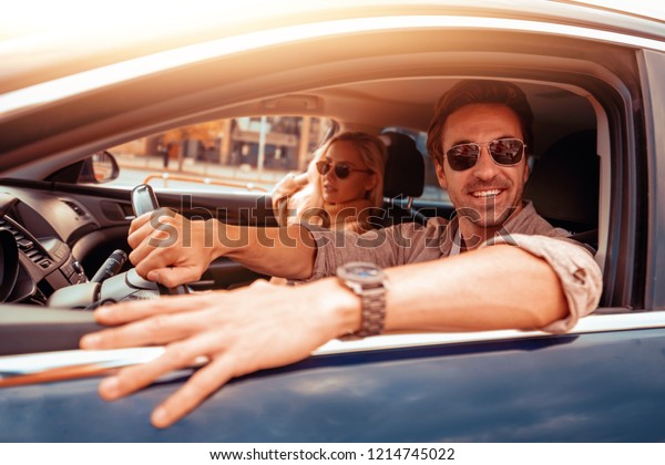 Enjoying road trip\
together.Leisure, road trip,people and travel concept -man and\
woman driving in car.