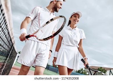 Enjoying spending time on the court. Beautiful young couple walking on the tennis court with smile. - Powered by Shutterstock