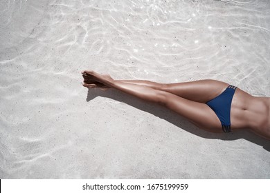 Enjoying suntan. Vacation concept. Top view of slim young woman in bikini in the swimming pool.